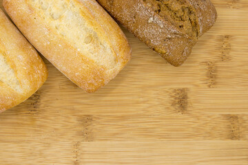 wheat and wheat-rye buns on a wooden board, close-up, copy space