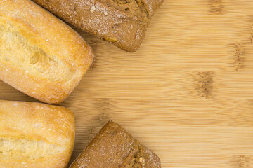 wheat and wheat-rye buns on a wooden board, close-up, copy space