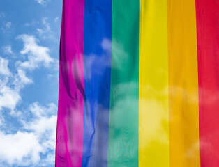 Rainbow flag in sunshine against blue sky