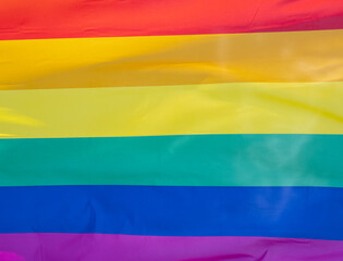 Rainbow flag in sunshine against blue sky