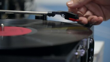 Male hands turning vintage turntable on. Close up a needle and a black record vinyl record spins.