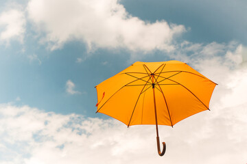 Yellow umbrella in the sky. Sunny umbrella in the sky, creating a summer, artistic mood on the street.
