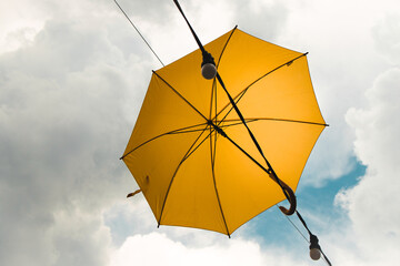 Yellow umbrella in the sky. Sunny umbrella in the sky, creating a summer, artistic mood on the street.