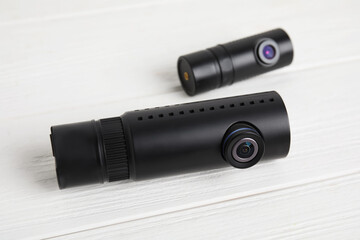 Black modern car cameras on white wooden table, closeup