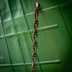 Rusty chain against the green hull of the boat