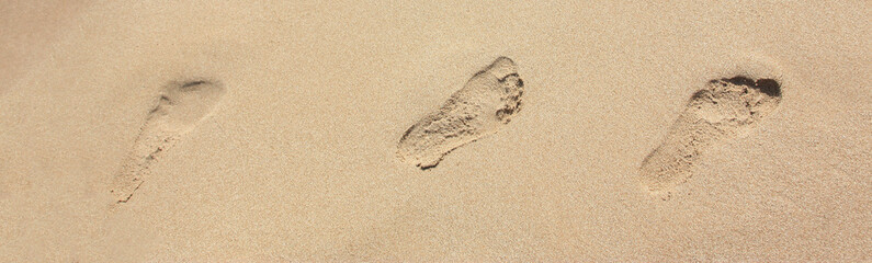 Fototapeta na wymiar Sand with footprints and on the sea side. Background banner