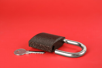 Modern padlock and key on red background. Space for text