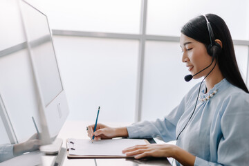 secretary operator wears a headset and microphone for consultant assistance support, the call center staff providing advice and assistance customers in smiling and happy manner