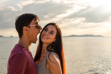 Portrait of cheeky boyfriend playing with girl friend at the beach in sunset. lovely couple dating on vacation. sea and sky background.