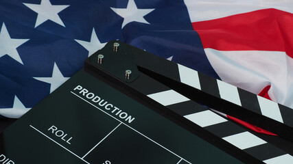 Black Clapper board or movie slate and Flag of the United States of America (USA.) on black...