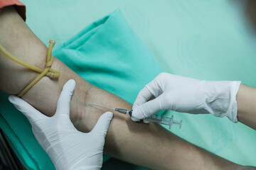 Close up Hand of nurse, doctor or Medical technologist in blue gloves taking blood sample from a...