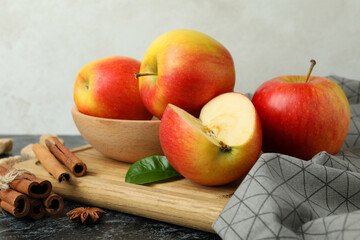 Board with tasty red apples on black smokey table