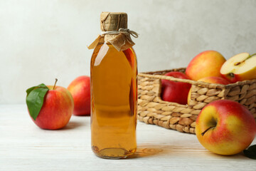 Homemade apple vinegar and ingredients on white wooden table