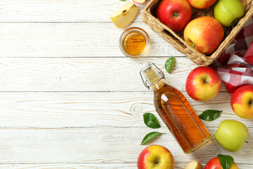 Homemade apple vinegar and ingredients on white wooden table