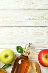 Homemade apple vinegar and ingredients on white wooden table