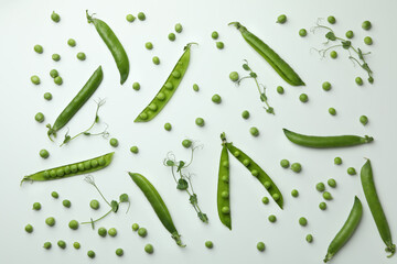 Green pea pods, seeds and twigs on white background