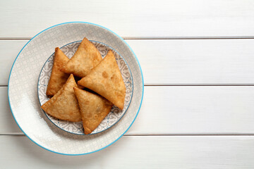 Fresh delicious crispy samosas on white wooden table, top view. Space for text