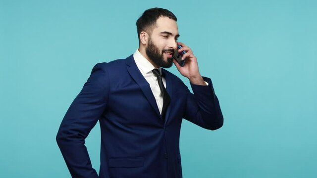 Portrait of attractive young office worker calls to colleague on cellular, has phone talk, try to arrange meeting discuss everything alive. Indoor studio shot isolated on blue background.