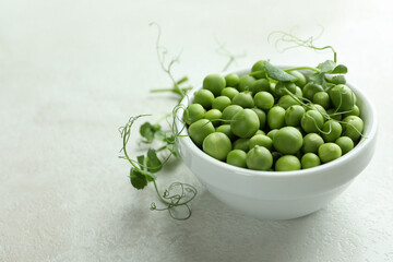 Bowl with pea seeds on white textured background