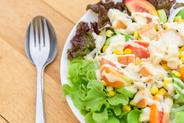 Mixed fresh vegetables salad in white dish on wood plate