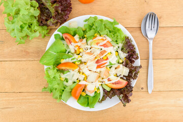 Mixed fresh vegetables salad in white dish on wood plate