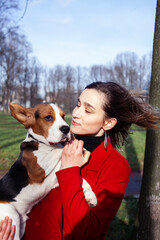 pretty young girl in red coat playing with dog outside in green park, lifestyle people concept