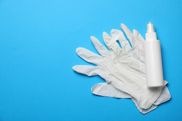 Medical gloves and hand sanitizer on light blue background, flat lay with space for text. Safety equipment