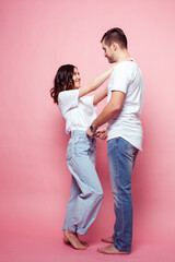 Fototapeta premium young cheerful caucasian couple together having fun on pink background, guy ang girl modern relationship, lifestyle people concept