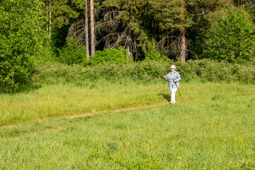 The grandmother is engaged in Scandinavian walking. An elderly woman goes in for sports.