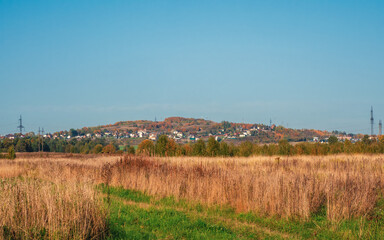 Fototapeta na wymiar Country life. A village on a hill. Village on the horizon across the autumn field.