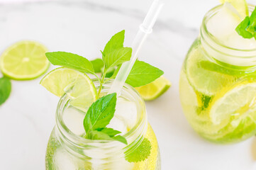 Lemon lemonade in mason jar glass made of fruit on a table background. Cold summer beverage. Mojito cocktail with lemon and mint.