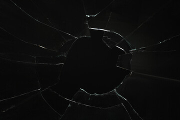 Closeup view of broken glass with cracks on black background