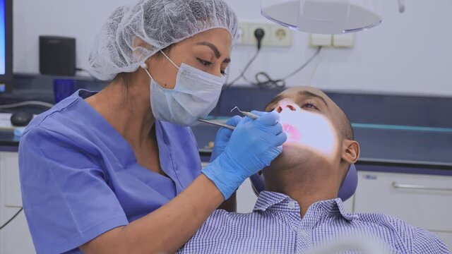 Qualified woman stomatologist pointing at teeth x-ray image on computer monitor explaining future treatment to patient in dental office