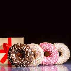 Donuts and a gift box over dark background 