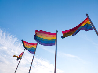 Some rainbow flags on blue sky background. Pride lgbt, gay flags being waved in the breeze. 