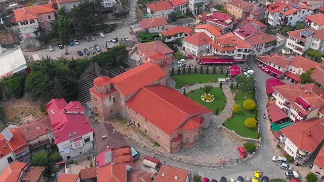 Orthodox church at old town of Ohrid, North Macedonia and village of houses with red roofs. Medieval old gothic architectures look beautiful from above sky with aerial drone 4K 30fps. 