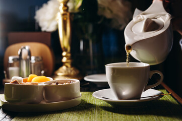 A woman with a cup of hot tea in her hands sits in the restaurant. The girl drinks aromatic tea. Enjoy the moment, take a break.