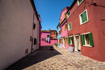 Old small multi colored houses (bright colors) in Burano island in a sunny spring day. Venice lagoon, UNESCO world heritage site, Veneto, Italy, southern Europe.