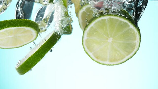 Super slow motion of falling lime slices with ice cubes into water. Filmed on high speed cinema camera, 1000 fps.