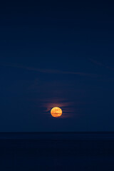 Roter Vollmond &uuml;ber dem Wasser in Hafenanlage