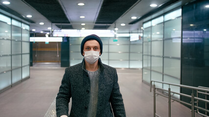 Man in Surgical Face Mask Walks with Suitcase in Airport. SARS-CoV-2 Coronavirus Pandemic Travel Restrictions.