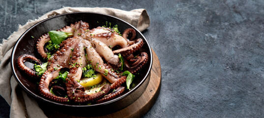 Grilled octopus served with spices and lemon on gray background. Seafood concept.