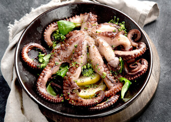 Grilled octopus served with spices and lemon on gray background. Seafood concept. © bit24
