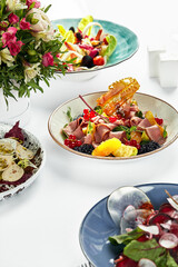 Duck breast salad on a festive table with white naperons. Cold smoked duck breast in a salad with fruit wedges.