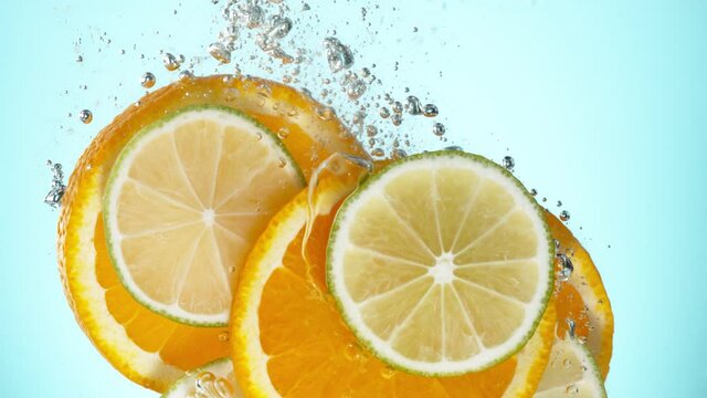 Super slow motion of falling lime, orange and lemon slices into water. Speed ramp effect. Filmed on high speed cinema camera, 1000 fps.