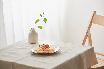 handmade pasta with ragout sauce on plate on vintage white table with colander and flowers