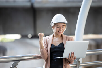 Young female architecture holding laptop while checking project at construction site.