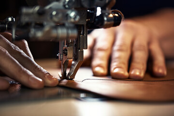 A sewing machine foot with the hands of a master close-up, a tailor makes a seam on a piece of...