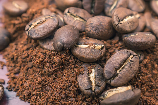 Roasted coffee beans lie on top of a pile of ground coffee © Николай Чекалин