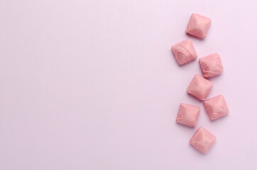 Top view of line of pink candies on the bright pink surface.Empty space